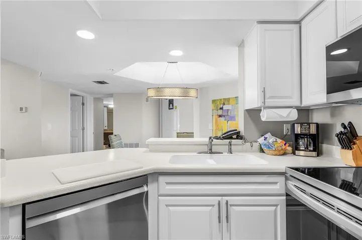 Kitchen featuring white cabinetry, integrated sink, stainless steel dishwasher, and recessed lighting
