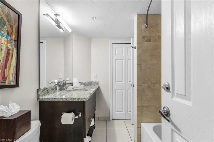Bathroom featuring a vanity with a granite-style countertop, undermount sink, and a large mirror