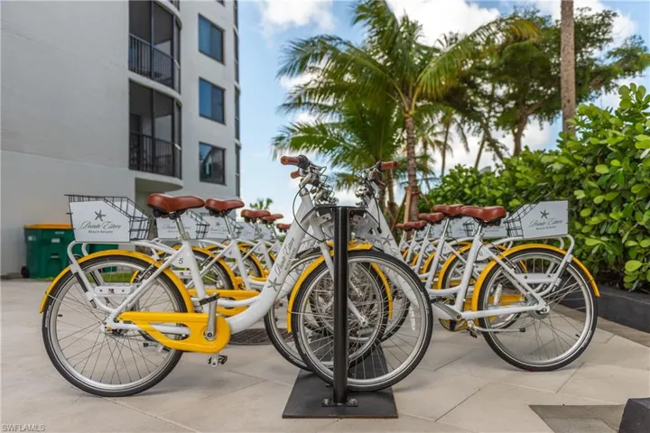 Community bike-share station featuring multiple yellow bicycles with comfortable saddles, integrated baskets, and all-terrain tires