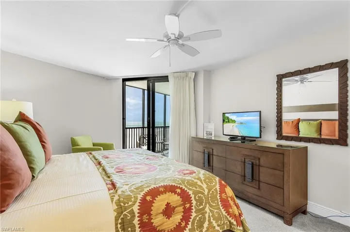 Sliding glass doors to outdoor balcony, ceiling fan, and wood-finish dresser