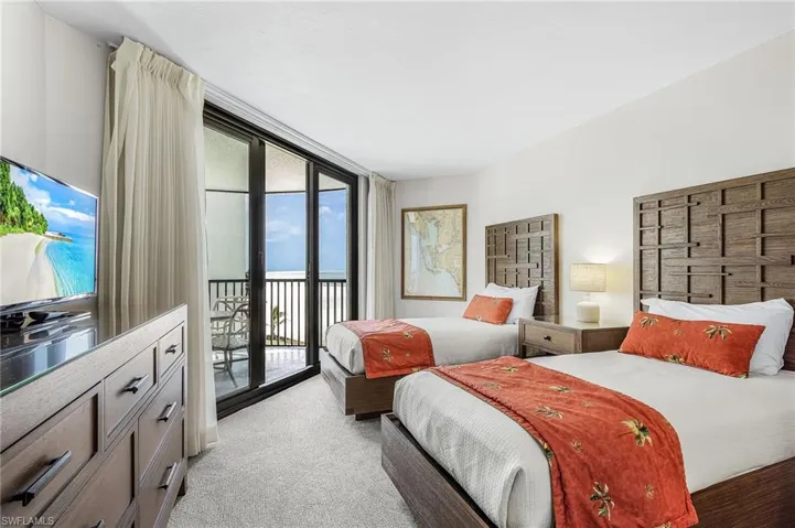Sliding glass doors opening to a private balcony, ocean backdrop, and built-in dresser