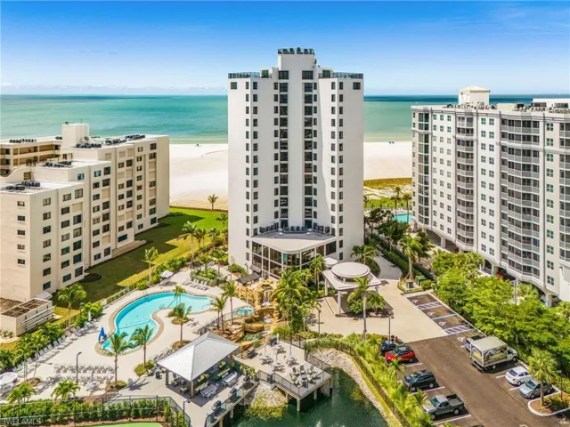 Expansive beachfront property featuring multiple high-rise buildings, a large swimming pool, and dedicated parking areas