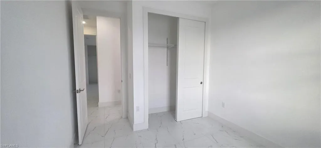 Unfurnished bedroom with light marble finish flooring and a closet