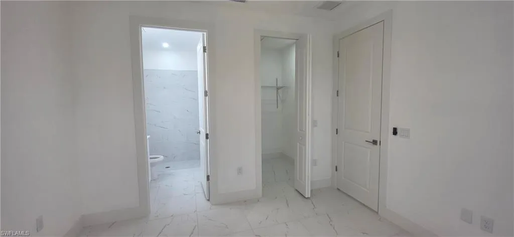 Hallway featuring light marble finish floors and baseboards
