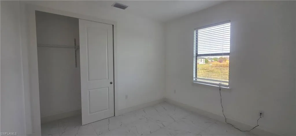 Unfurnished bedroom with light marble finish flooring and a closet