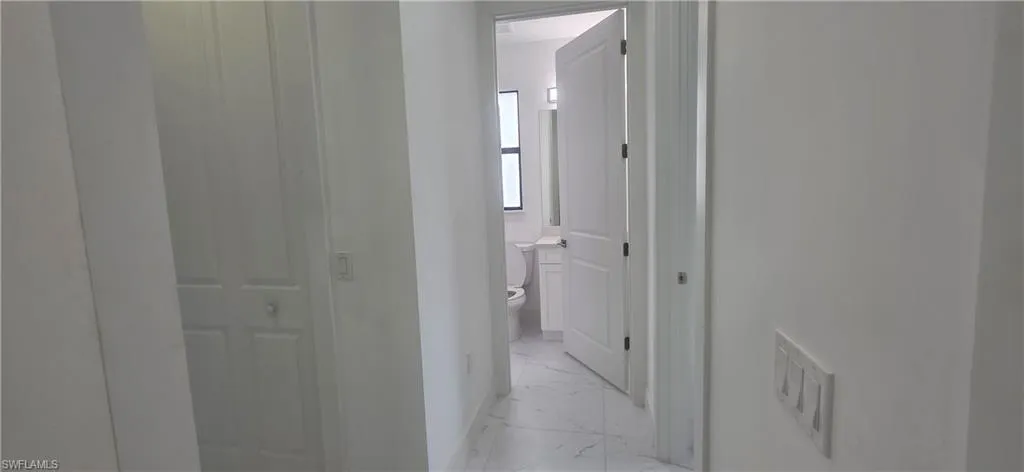 Corridor featuring light marble finish floors and baseboards
