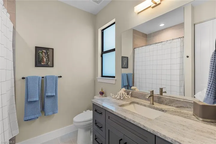 Bathroom with vanity, tile patterned floors, toilet, and a shower with shower curtain
