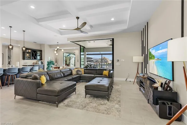 Living room featuring beamed ceiling, coffered ceiling, and ceiling fan