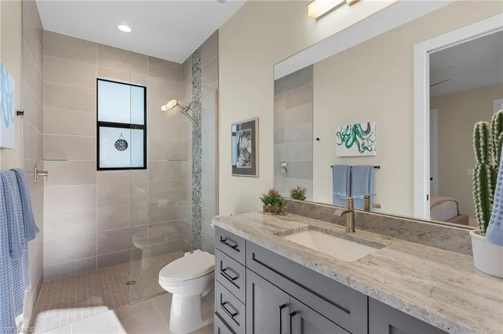 Bathroom with vanity, a tile shower, tile patterned floors, and toilet
