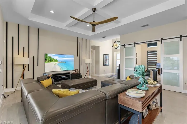 Living room with coffered ceiling, ceiling fan, a barn door, and beam ceiling