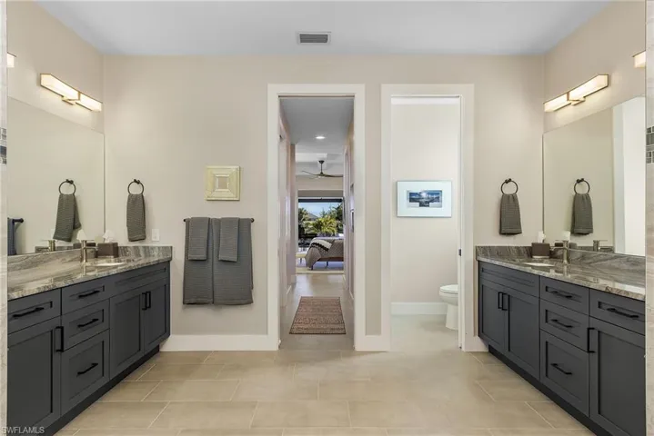 Bathroom featuring vanity, ceiling fan, tile patterned flooring, and toilet