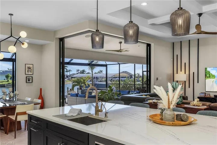 Kitchen with beamed ceiling, sink, hanging light fixtures, coffered ceiling, and light stone countertops