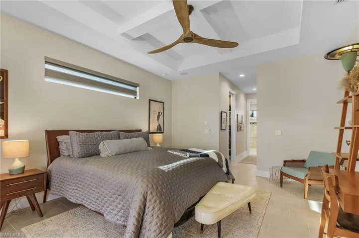 Bedroom with multiple windows, ensuite bath, a raised ceiling, and ceiling fan