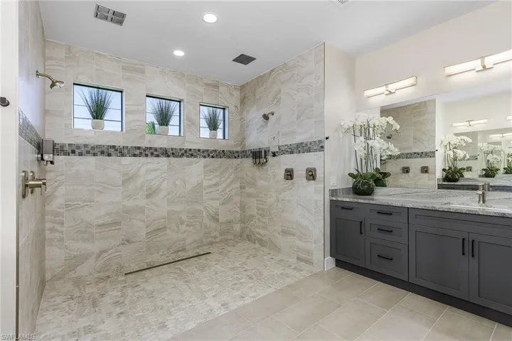 Bathroom with vanity, a tile shower, and tile patterned floors