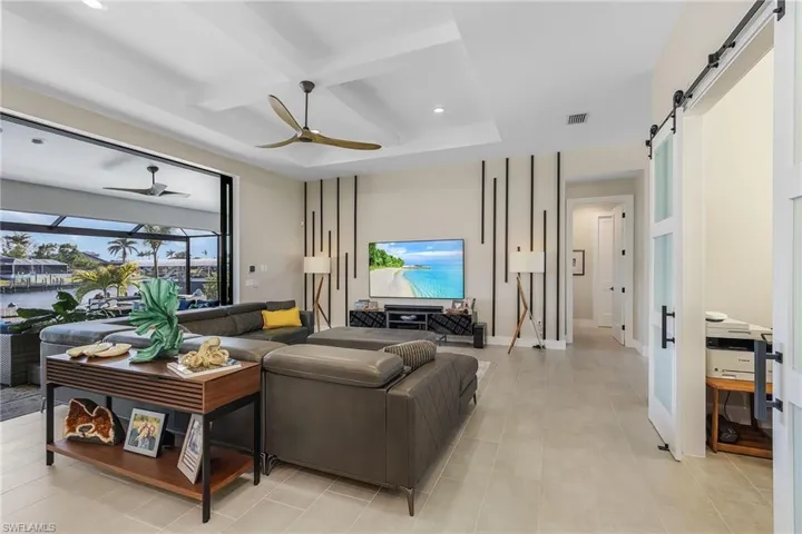 Living room with coffered ceiling, ceiling fan, a barn door, and beam ceiling