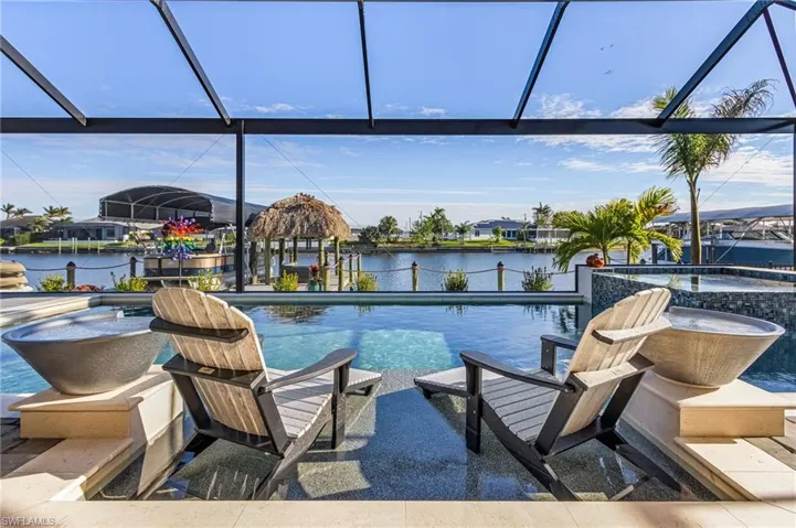 View of swimming pool with a water view, an in ground hot tub, and a lanai
