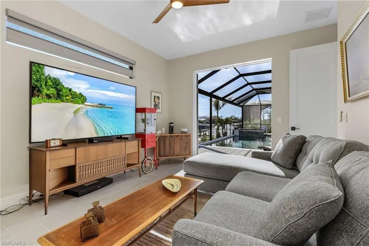 Tiled living room with lofted ceiling, a wealth of natural light, and ceiling fan