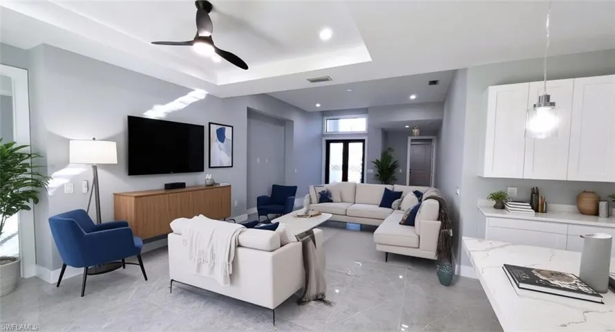 Virtual staging. Living room with a tray ceiling, ceiling fan, recessed lighting, and light marble finish flooring