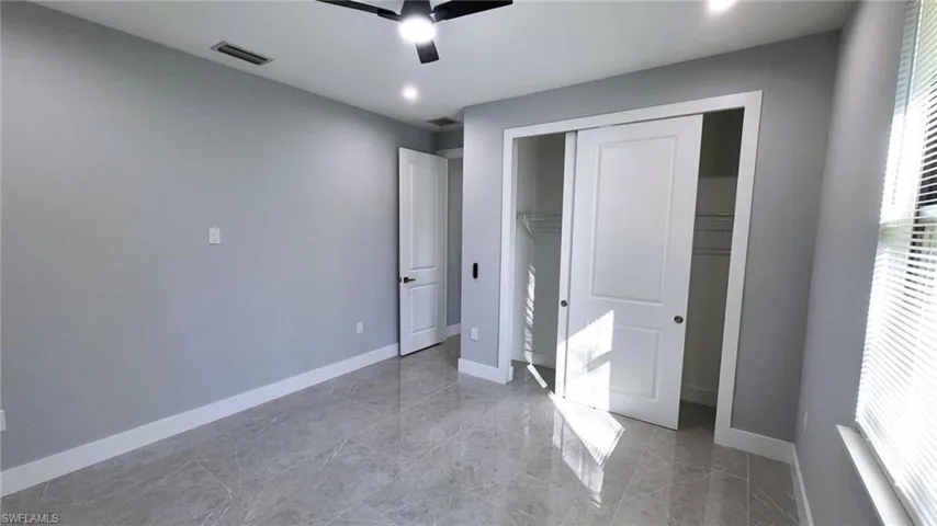 Unfurnished bedroom with a closet, a ceiling fan, light marble finish flooring, and recessed lighting