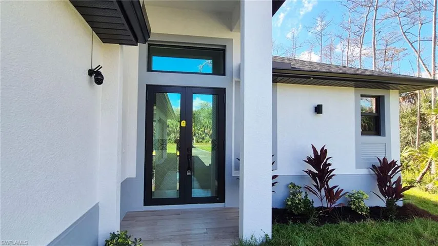 Doorway to property featuring french doors, stucco siding, and a shingled roof
