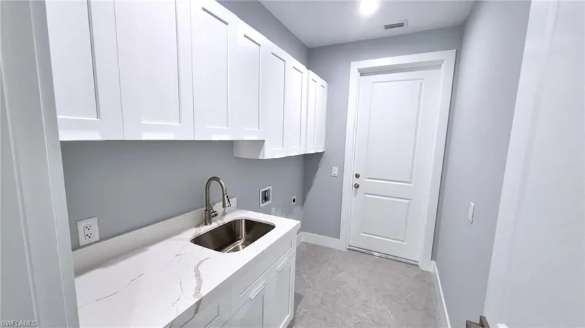 Laundry area featuring hookup for a washing machine, hookup for an electric dryer, cabinet space, and light tile patterned floors