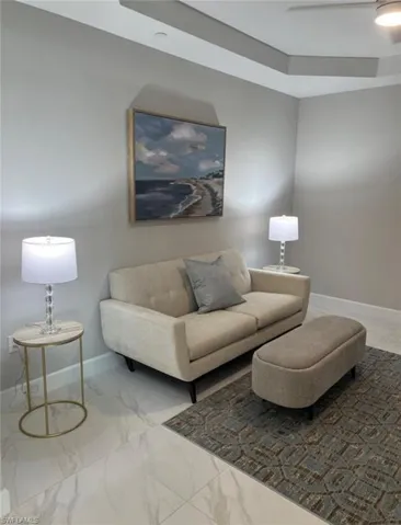 Living room with a raised ceiling and light marble finish floors