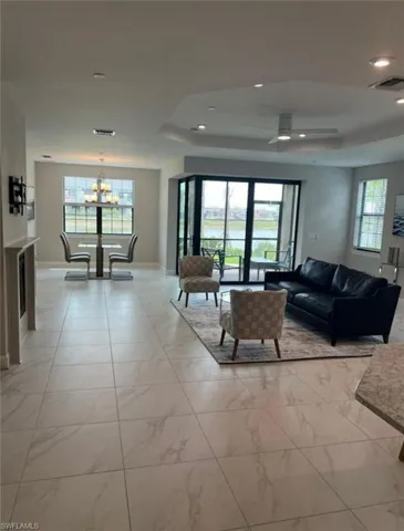 Living room featuring plenty of natural light, light marble finish floors, a chandelier, and a raised ceiling