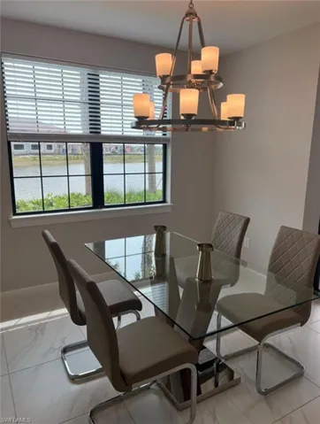 Dining room featuring a water view, a chandelier, and light marble finish flooring