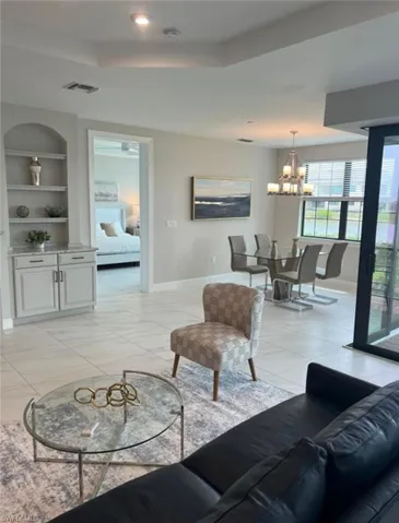 Living area with built in features, a tray ceiling, and suspended lighting