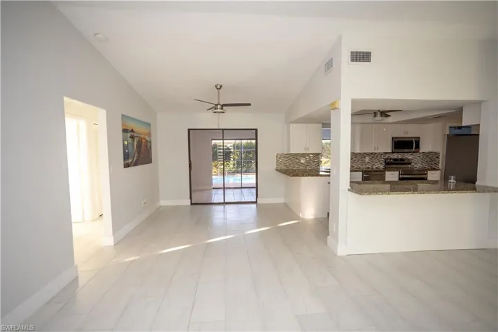 Kitchen featuring ceiling fan, appliances with stainless steel finishes, dark stone countertops, white cabinets, and kitchen peninsula