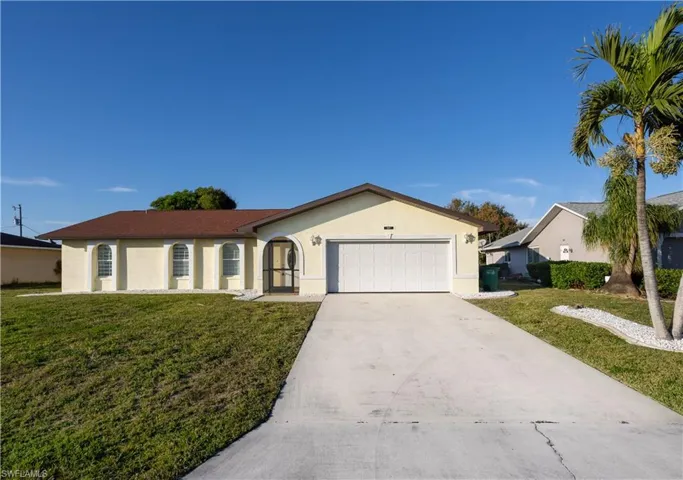 Ranch-style home with a garage and a front lawn