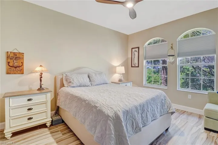Neutral walls, wood-finish flooring, two arched windows, and a three-blade ceiling fan with integrated lighting