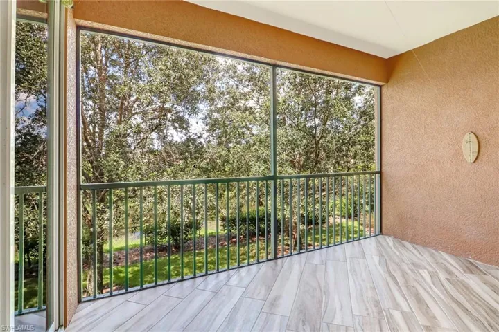 Screened-in balcony featuring wood-finish tile flooring, stucco walls, and metal railings