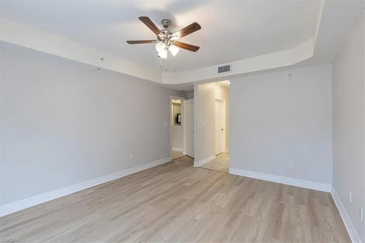 Unfurnished room with light wood-style flooring, a tray ceiling, and a ceiling fan