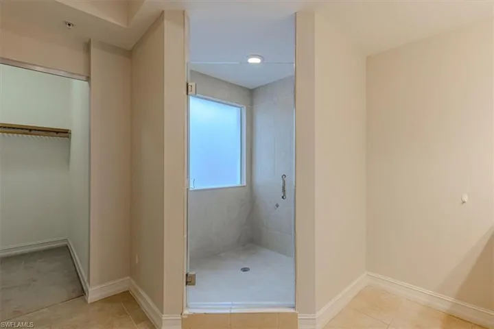 Bathroom featuring a stall shower, light tile patterned flooring, and a spacious closet
