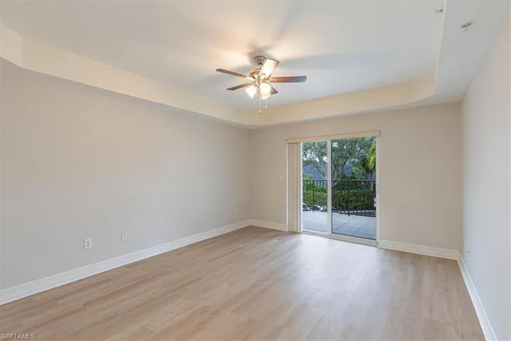 Spare room with a raised ceiling, light wood finished floors, and ceiling fan