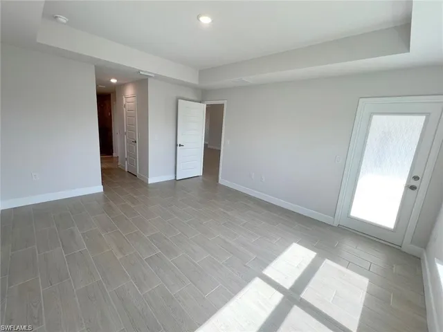 Unfurnished room with a raised ceiling, wood tiled floors, and recessed lighting