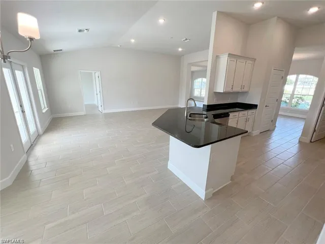 Kitchen with a peninsula, wood finish floors, white cabinets, recessed lighting, and dark stone countertops