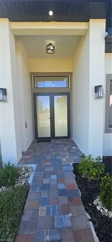 Prairie-style home featuring stucco siding, decorative driveway, and a front yard