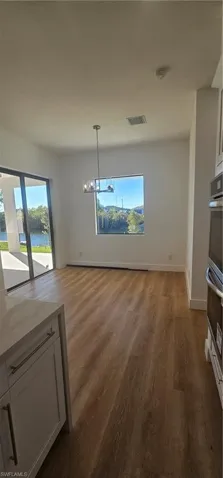 Kitchen with pendant lighting, white cabinets, dishwasher, light wood-style flooring, and light stone countertops