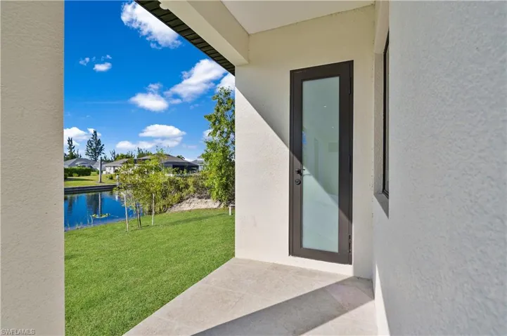 Doorway to property featuring a yard, a patio, stucco siding, and a water view