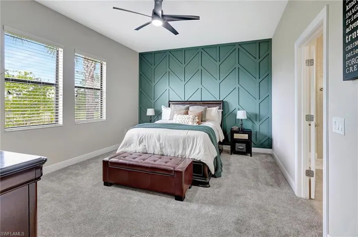 Bedroom with an accent wall, light colored carpet, and ceiling fan