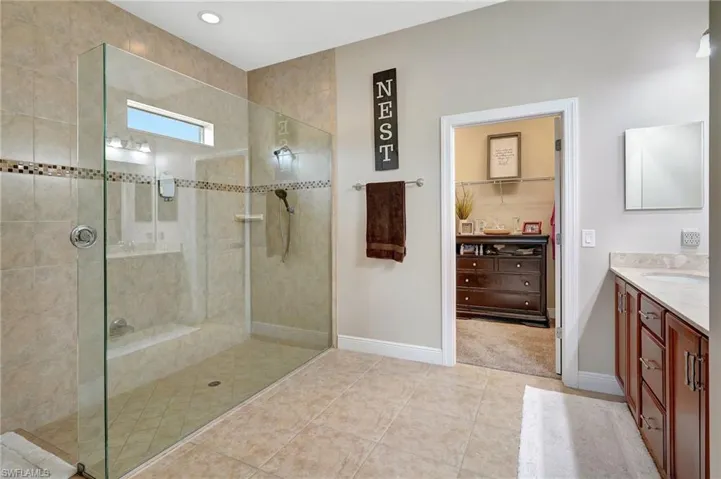 Bathroom featuring a shower stall, vanity, a spacious closet, and light tile patterned flooring