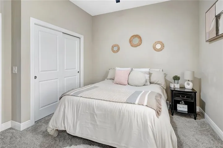Bedroom with light colored carpet, a ceiling fan, and a closet