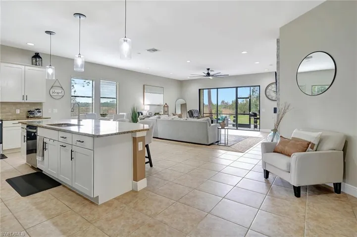 Kitchen with pendant lighting, granite counters, open floor plan, white cabinets, and a kitchen bar