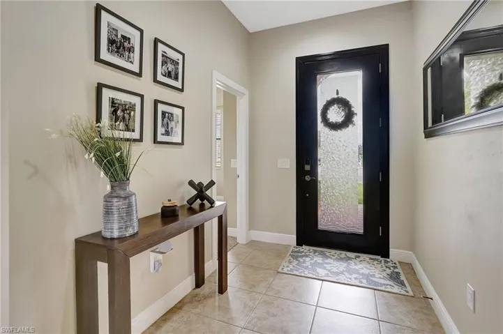 Foyer with light tile patterned flooring and baseboards