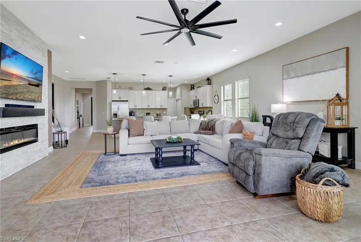 Living room featuring light tile patterned floors, ceiling fan, recessed lighting, and a large stone fireplace