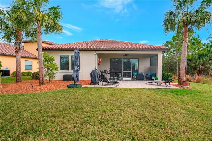 Back of house featuring stucco siding, ceiling fan, a tile roof, a yard, and a patio