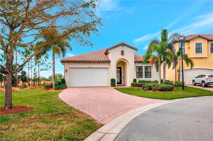 Mediterranean / spanish home featuring stucco siding, decorative driveway, a garage, a front yard, and a tile roof