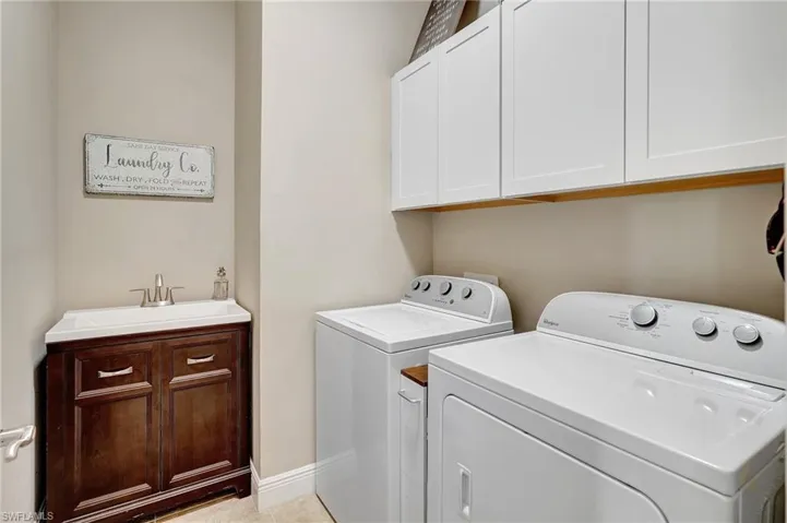 Laundry room with cabinet space, washing machine and clothes dryer, and light tile patterned flooring